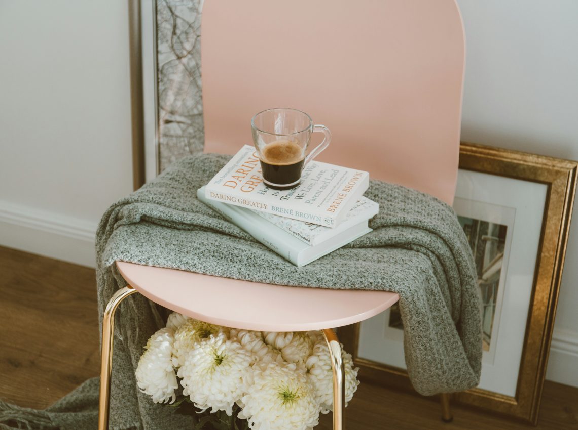 Book on a chair with cozy blanket and coffee